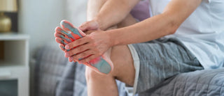 Person holding the bottom of their foot, with highlighted areas indicating foot pain or pressure.