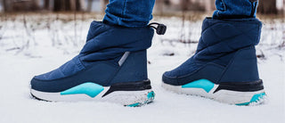 Person wearing insulated winter boots while standing on snow outdoors.